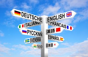 Multilingual languages and flags sign post against blue sky